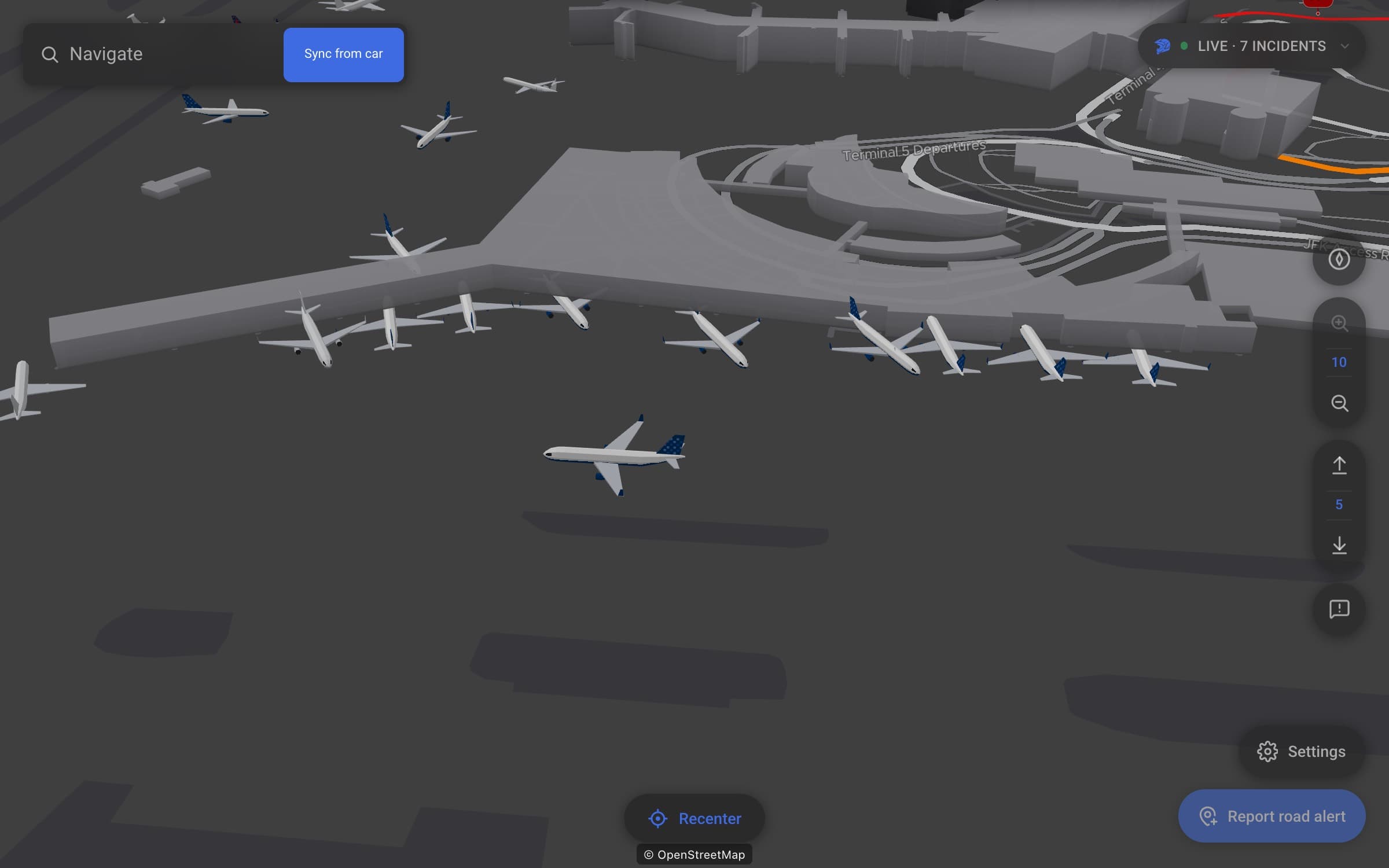 A tilted 3D night map of JFK Terminal 5: JetBlue jets with their blue tail marks parked nose-in along the concourse, another JetBlue jet taxiing past in the foreground, and more aircraft on the taxiways beyond.